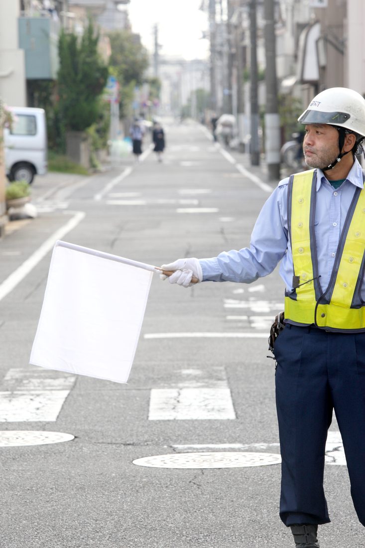 交通誘導の現場で車両を誘導するジェイエヌティの警備員
